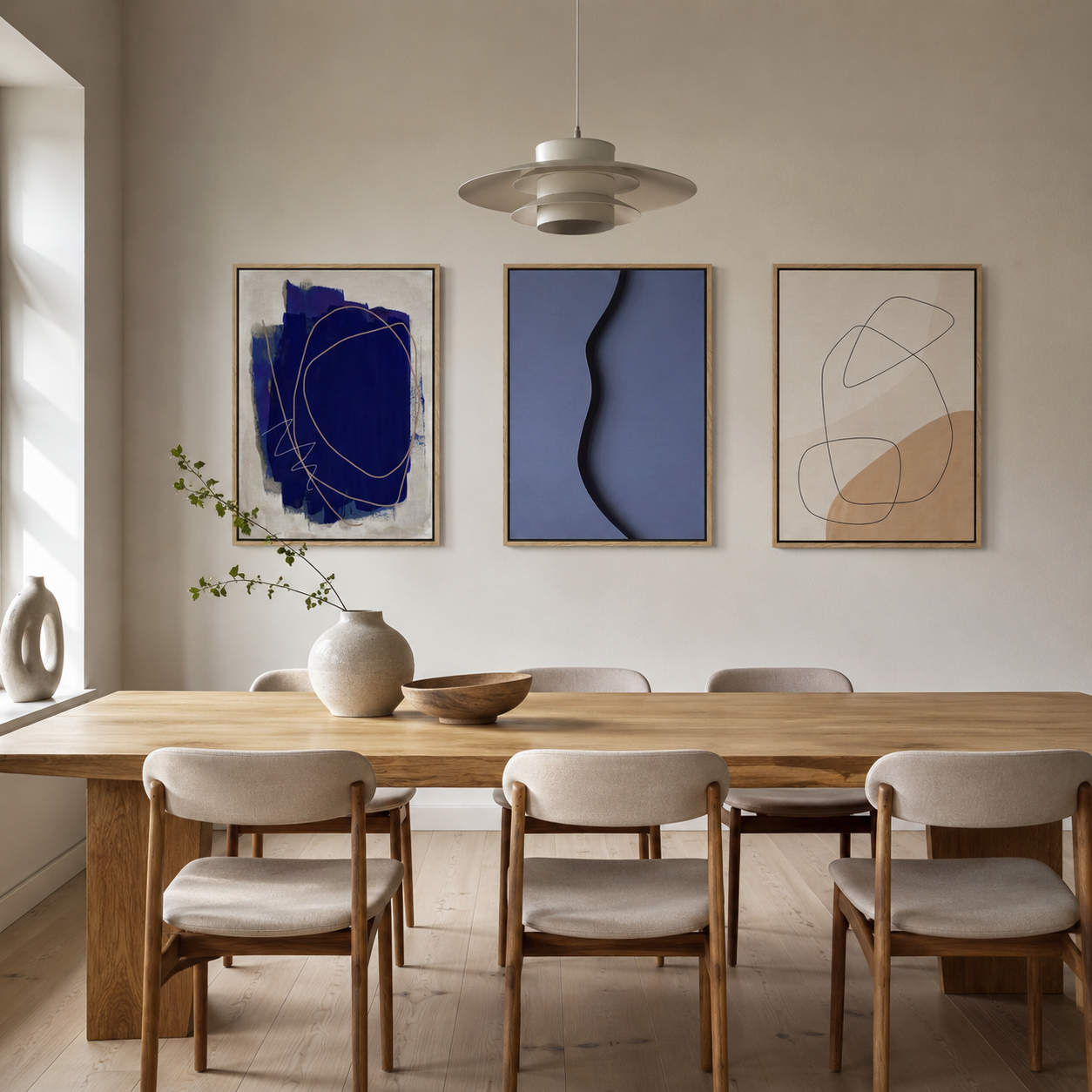 Three blue and cream abstract prints above a pale oak dining table