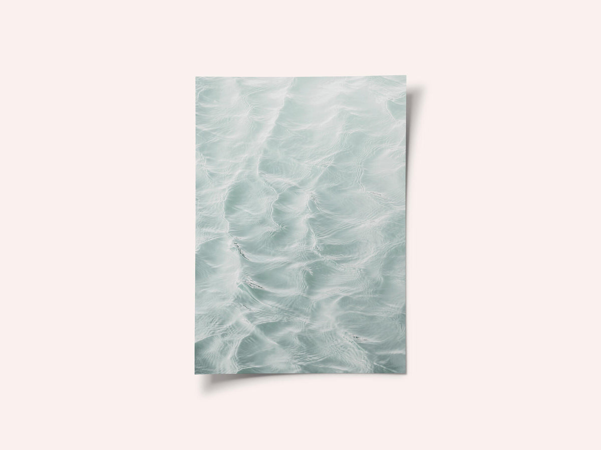 Sunlit rippled water surface in pale sea green with soft white light patterns